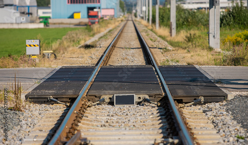 Railway crossing viewed from the rails, asphalt road crossing railway line using rubber elements over the train tracks.