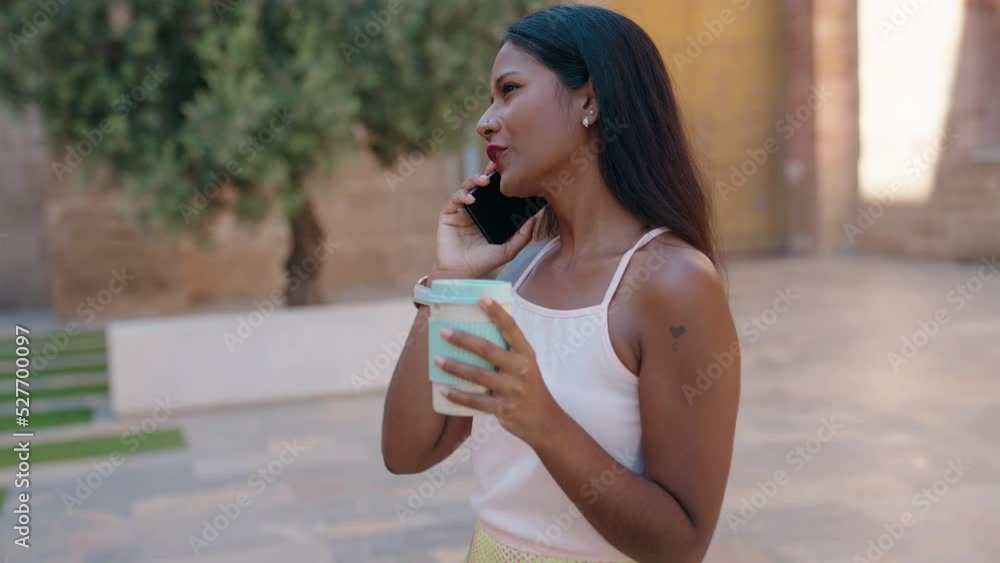Young beautiful woman talking on smartphone drinking coffee at street Young beautiful woman talking on smartphone drinking coffee at street