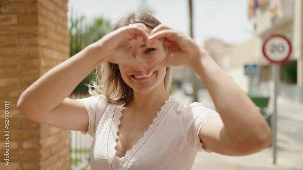 Young caucasian woman smiling confident doing heart gesture with hands at street Young caucasian woman smiling confident doing heart gesture with hands at street