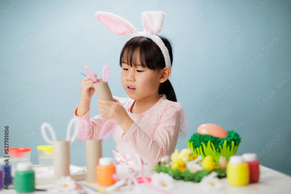 young girl making easter craft against plain background young girl making easter craft against plain background