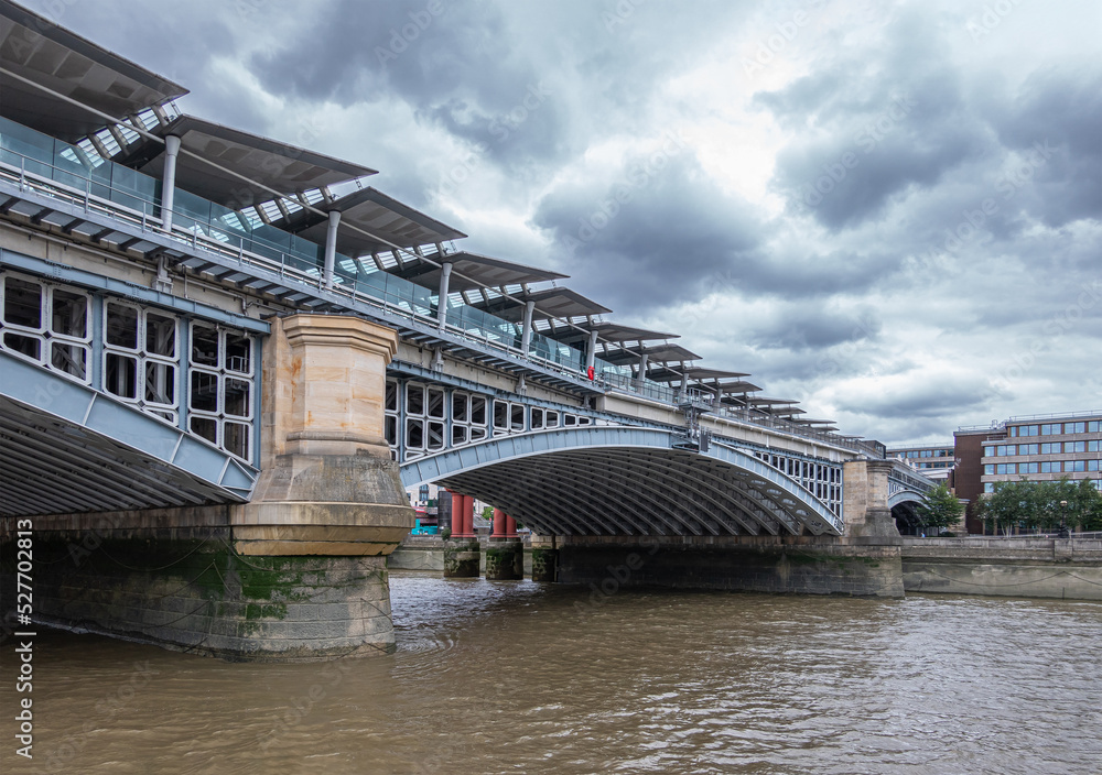 London, England, UK - July 6, 2022: From Thames River. South shore landing of Blackfriars railway bridge under blueish cloudscape. 