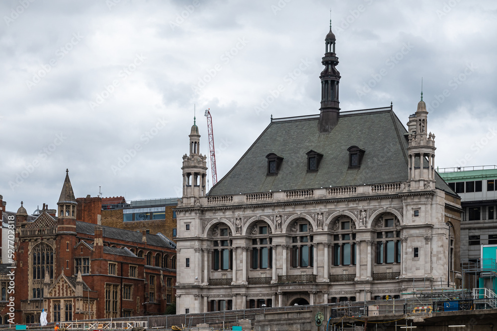 London, England, UK - July 6, 2022: From Thames River. 60 Victoria Embankment, historic gray stone mansion with small towers and facade statues. now JP Morgan offices under cloudy sky