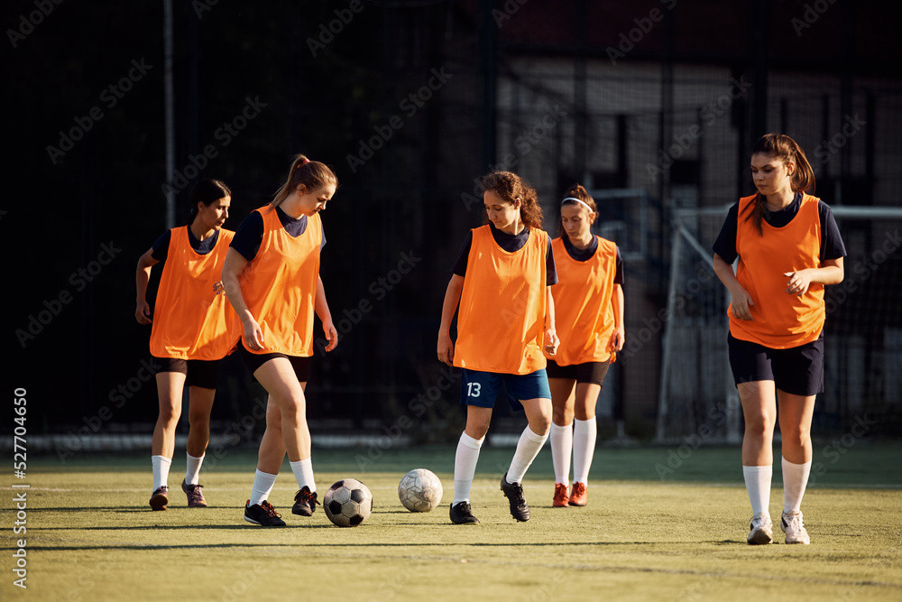 Female soccer players having sports training at stadium.