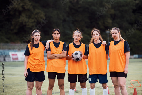 Team of female soccer players standing on playing field and looking at camera.