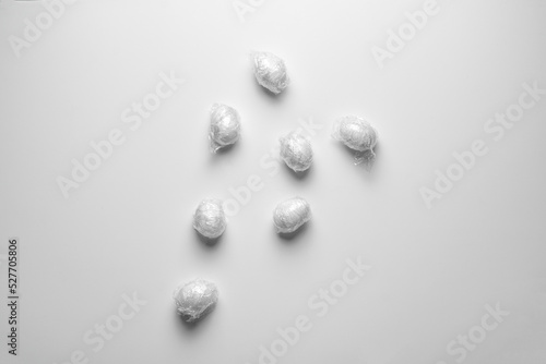 the easter eggs wrapped in traslucent plastic foil flat lay on the pastel background