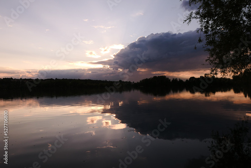 Dramatic sky over the water in rural scene. Symmetry of clouds in a lake at sunrise or sunset. © Bruno