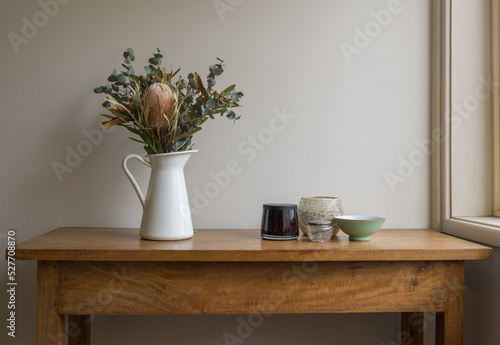 фотографія Australian native flowers in white jug wtih little bowls on oak side table again