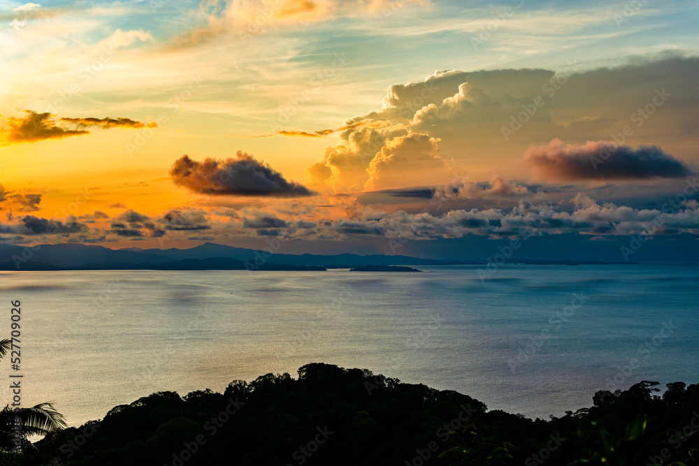 Sun sets behind massive cumulus clouds over the Gulf of Nicoya in Puntarenas, Costa Rica