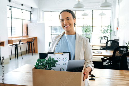 Schilderij op canvas Happy young brazilian or hispanic female employee, holding cardboard box, standi