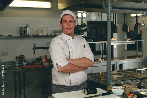 Portrait of handsome male chef in uniform standing on kitchen of restaurant