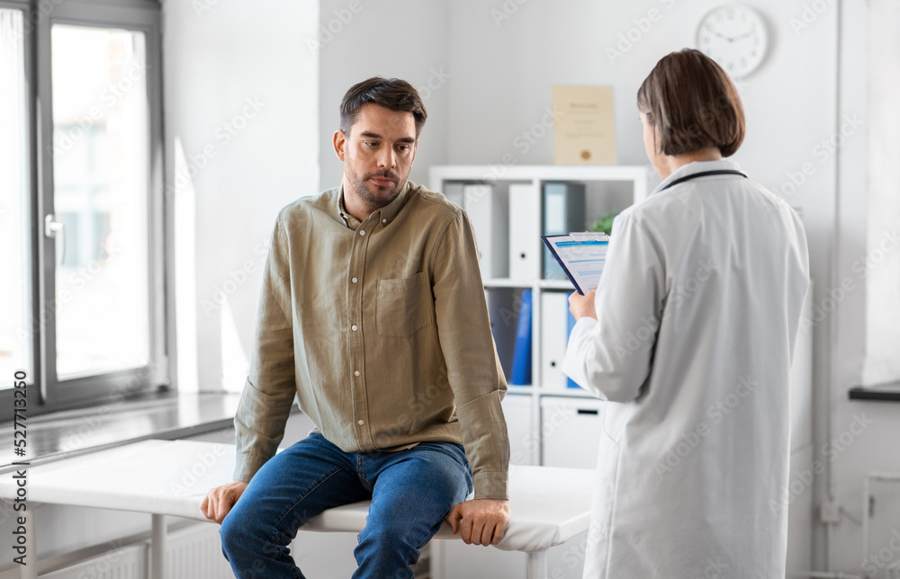 Obraz premium medicine, healthcare and people concept - female doctor with clipboard and male patient having health problem at hospital