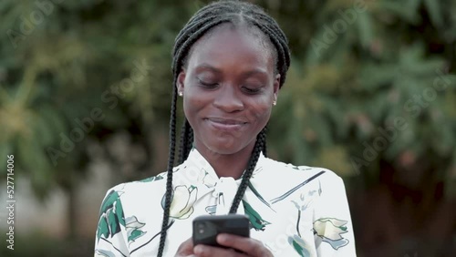 Beautiful African American lady texting and smiling on mobile phone