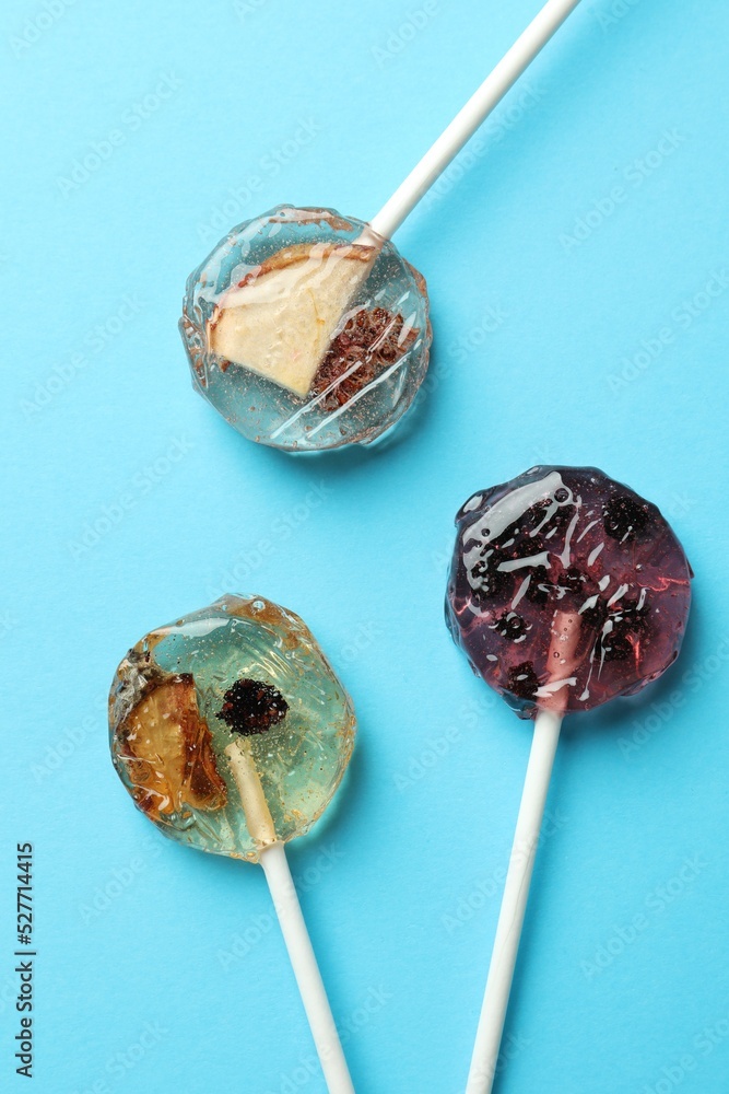 Sweet colorful lollipops with berries on light blue background, flat lay Sweet colorful lollipops with berries on light blue background, flat lay