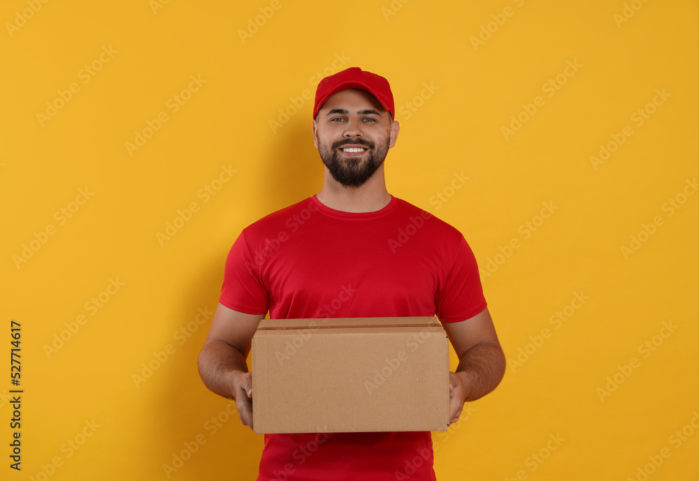 Courier holding cardboard box on yellow background Courier holding cardboard box on yellow background