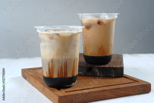 Iced coffee in a plastic cup on white and grey background 