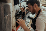 Handsome worker in uniform repairing coffee machine in a workshop