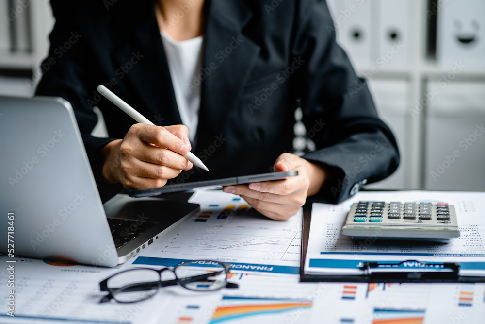 Businesswomen or Accountants use a tablet to work with financial statements and analyze company financial reports. investment, balance sheets, taxes, planning and business strategies concept. Businesswomen or Accountants use a tablet to work with financial statements and analyze company financial reports. investment, balance sheets, taxes, planning and business strategies concept.
