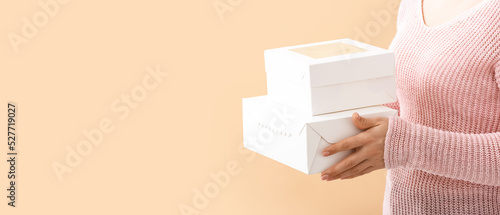 Woman holding cardboard boxes on beige background with space for text