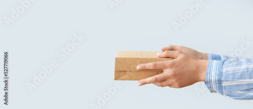 Hands holding cardboard box on light background with space for text