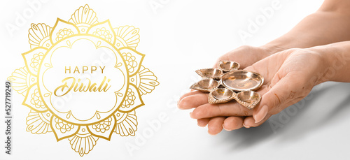 Female hands with diya lamp...