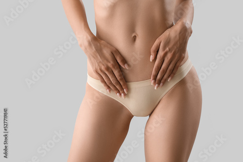 Slim young woman in underwear on light background photo