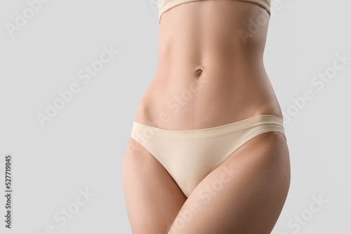 Slim young woman in underwear on light background