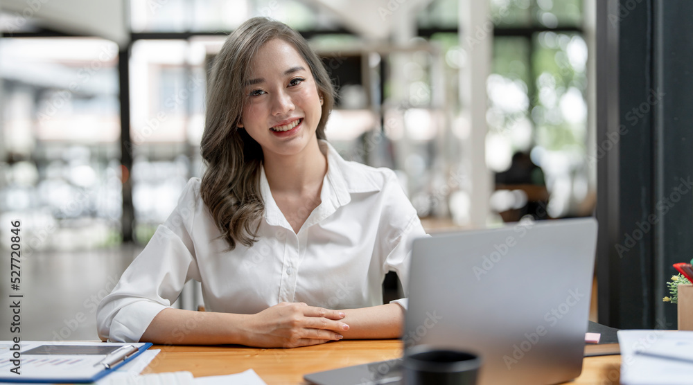 Image of young beautiful joyful woman smiling while working with laptop in office Image of young beautiful joyful woman smiling while working with laptop in office