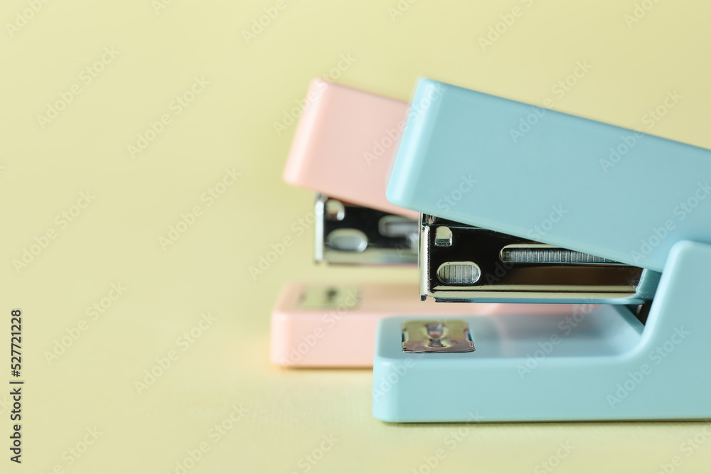 Office staplers on color background, closeup Office staplers on color background, closeup