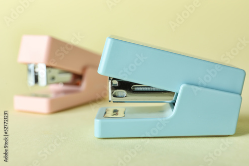 Office staplers on color background, closeup
