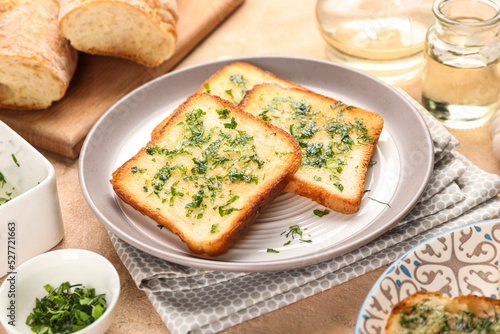 Plate with slices of delicious toasted garlic bread on table, closeup