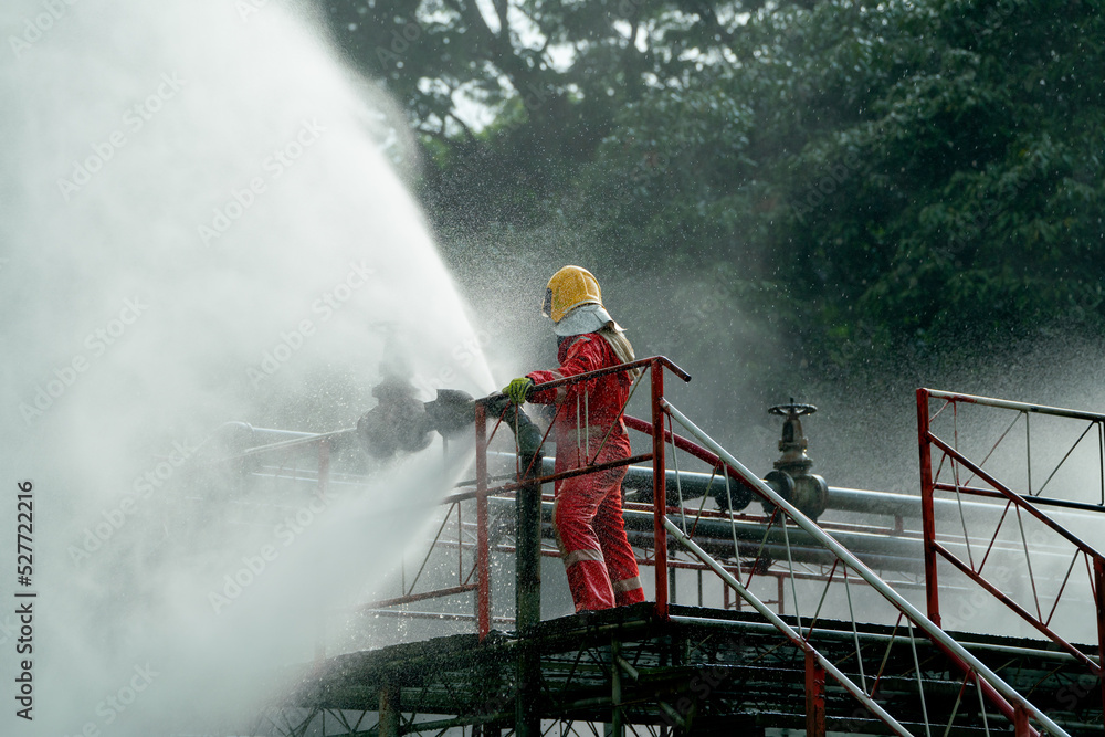 Fototapeta premium Firefighter try to extinguish or get rid of fire from gas pipe on top of building and he protect themselves by using water curtain.