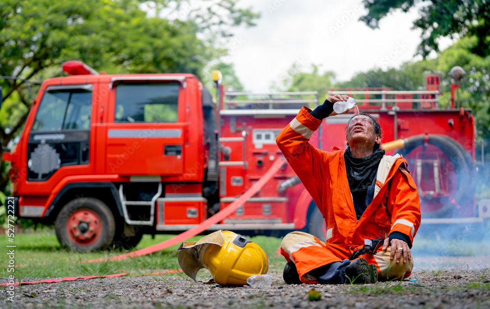 Firefighter sit in front of fire truck or fire engine and use water pour over his face look like he finish and succes to distinguish fire. Firefighter sit in front of fire truck or fire engine and use water pour over his face look like he finish and succes to distinguish fire.