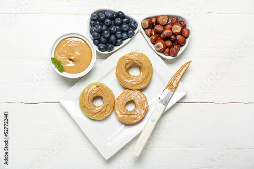 Wallpaper Mural Plate of apple rounds with nut butter, hazelnuts and blueberry on light wooden background Torontodigital.ca