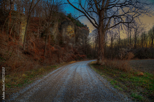 Down a Gravel Road at dusk by a large bluff 