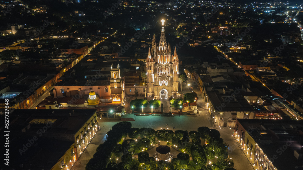 Fototapeta premium the church Parroquia Archangel Jardin Town Square Night Tree Decoraciones San Miguel de Allende, México. Parroaquia. Night and morning light in a drone view.