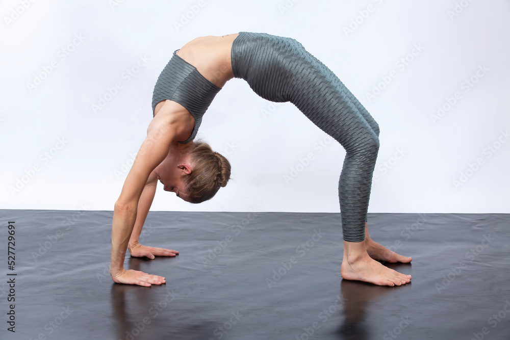 Yound woman in gray yoga suit doing a wheel pose. Yound woman in gray yoga suit doing a wheel pose.