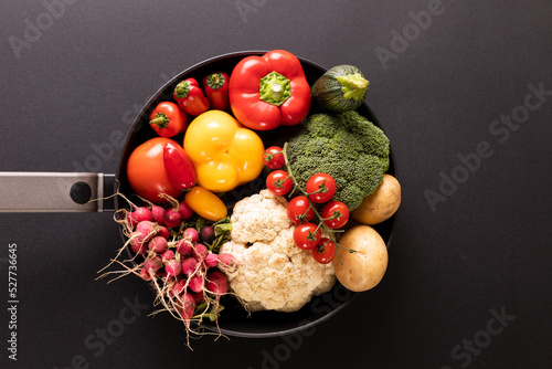 Directly above shot of various colorful vegetables in frying pan on black background