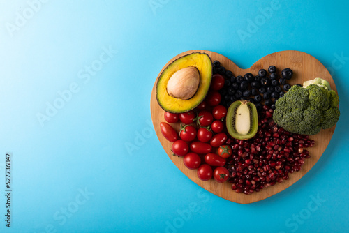 Directly above view of healthy food on heart shaped cutting board over blue background photo