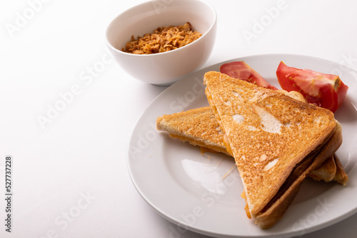 High angle view of cheese sandwich toast served with tomato slices in plate on white background
