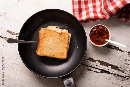 Directly above view of fresh cheese sandwich in cooking pan by dip bowl on wooden table