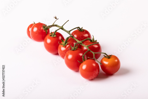 Close-up of fresh red cherry tomatoes twig against white background