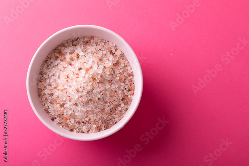 Directly above shot of himalayan salt in bowl on pink background with copy space