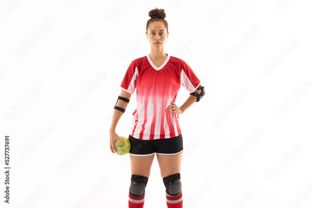 Biracial young female handball player standing with ball and hand on hip against white background Biracial young female handball player standing with ball and hand on hip against white background