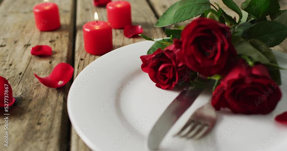 Candles and red roses on plate on wooden background at valentine's day