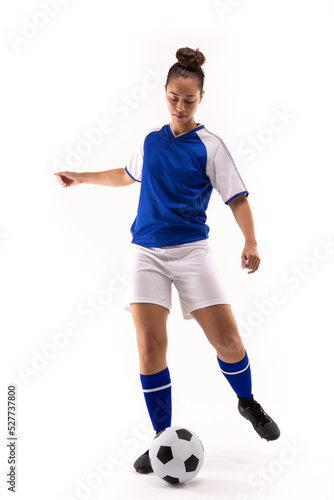 Full length of biracial young female soccer player kicking soccer ball against white background © WavebreakMediaMicro
