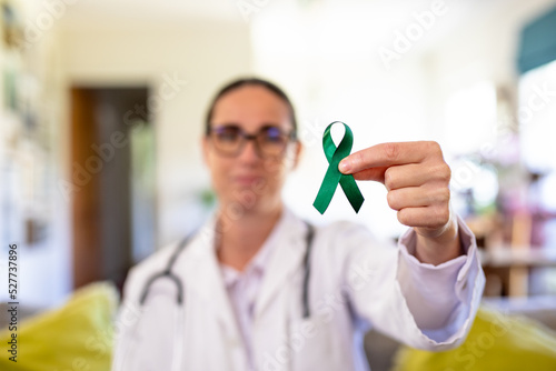 Mature caucasian female doctor showing mental health awareness ribbon, copy space