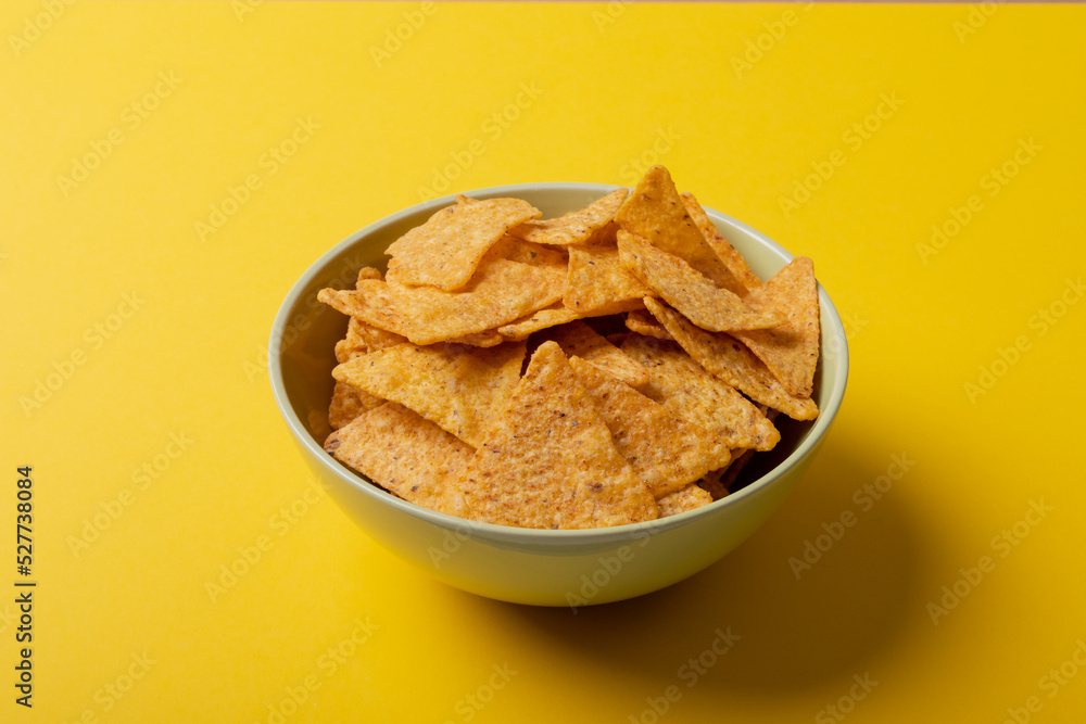 Close-up of nacho chips in bowl over yellow background Close-up of nacho chips in bowl over yellow background