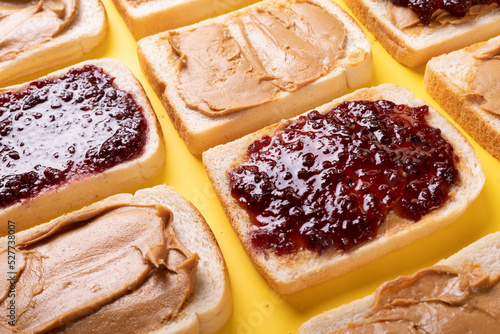 Full frame shot of bread slices with preserves and peanut butter arranged on yellow background