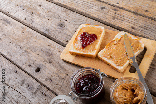 High angle view of open face peanut butter and jelly sandwich on serving board with jars at table