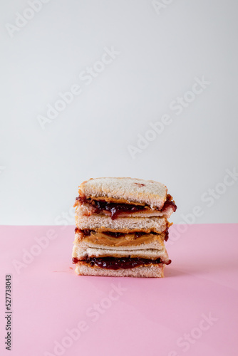 Stack of peanut butter and jelly sandwiches on table against gray background with copy space